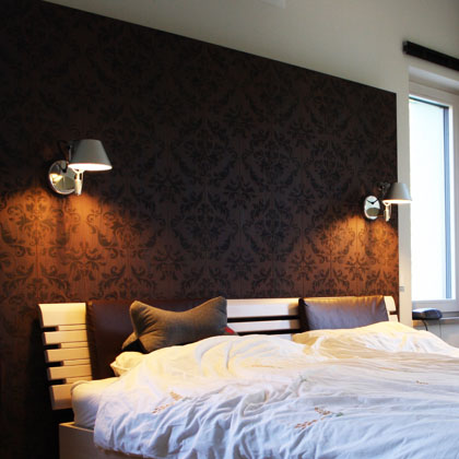Schlafzimmer dessen Wand mit dunklem, gemustertem Holz verkleidet ist